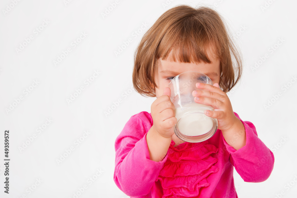 Little girl drinking milk, on a gray background Little girl drinking milk, on a gray background
