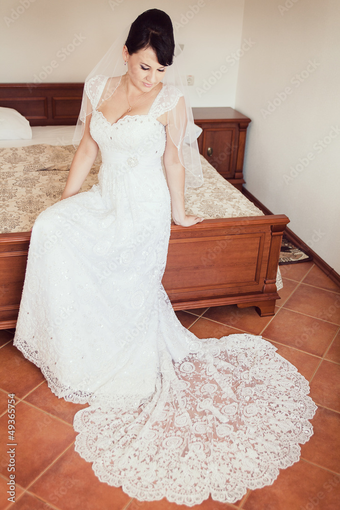 bride in wedding dress sitting on bed waiting for groom bride in wedding dress sitting on bed waiting for groom