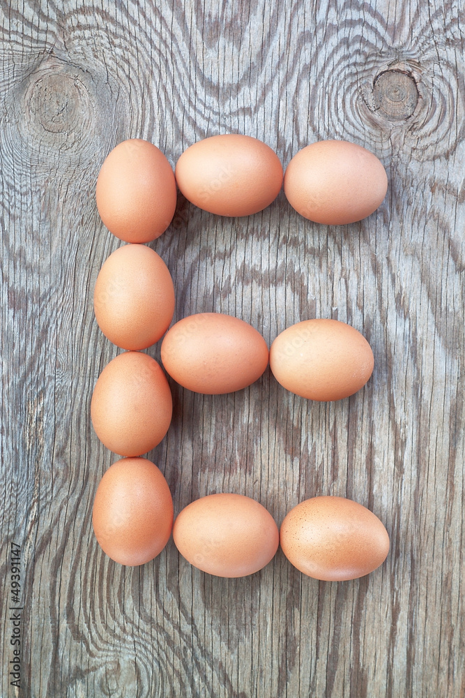 A letter e from the eggs for easter. On a wooden texture. A letter e from the eggs for easter. On a wooden texture.