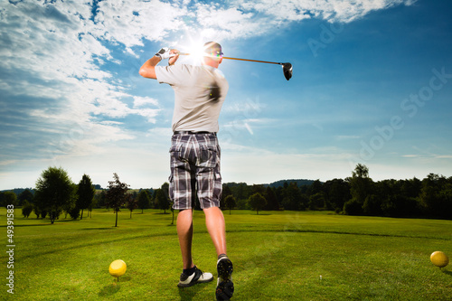 Young golf player on course doing golf swing