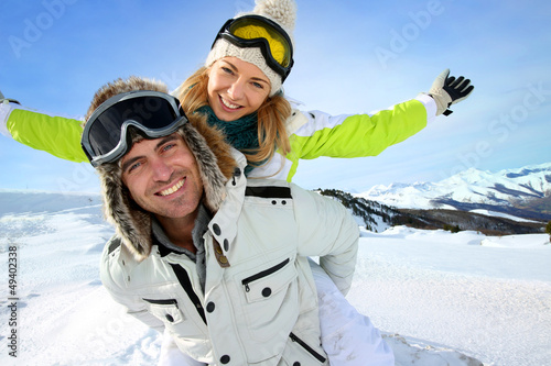 Fototapeta Naklejka Na Ścianę i Meble -  Cheerful snowboarder holding girlfriend on his back