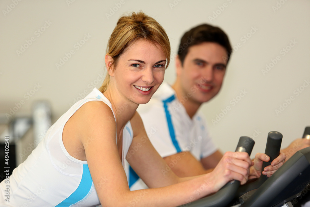 People exercising on bicycles in fitness gym People exercising on bicycles in fitness gym