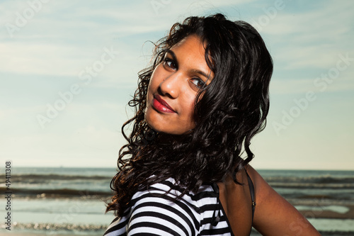 Pretty indian girl with long hair on the beach in summer.