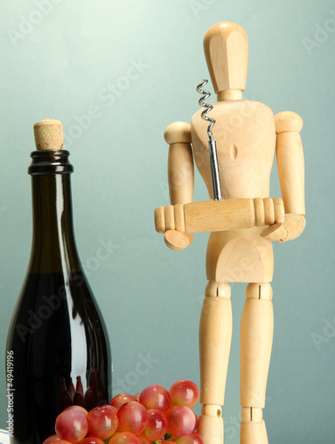 Mannequin with corkscrew and wine bottle, on grey background