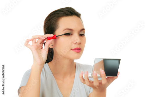 Isolated Asian woman applying mascara on white.