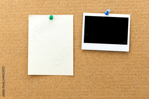 Blank photo frame and paper sheets on the cork board