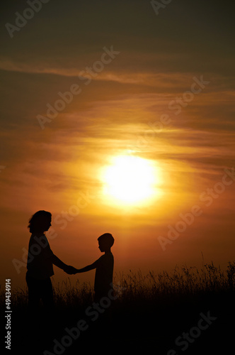 Silhouette of mother and child with sunset background