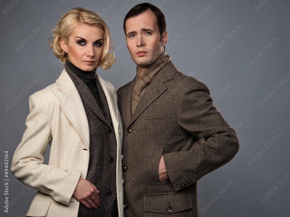 Elegant couple in coats isolated on grey