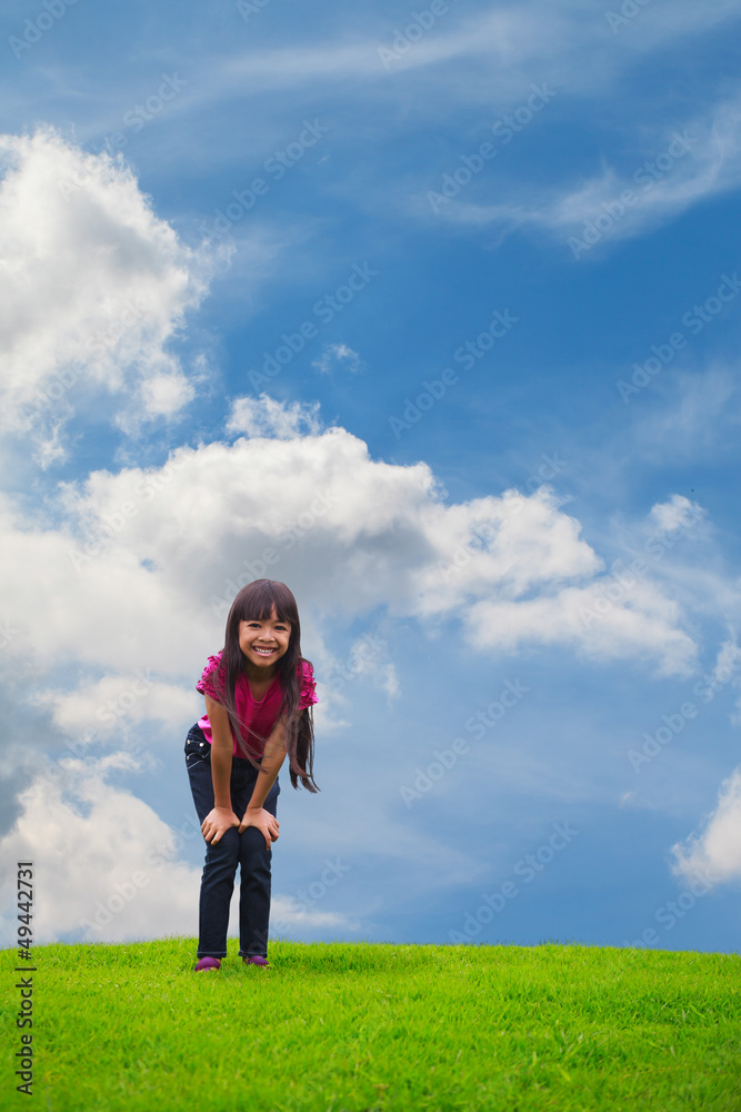 Smiling asian little girl standing on green grass