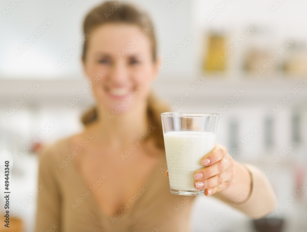 Closeup on young woman holding out glass of milk Closeup on young woman holding out glass of milk