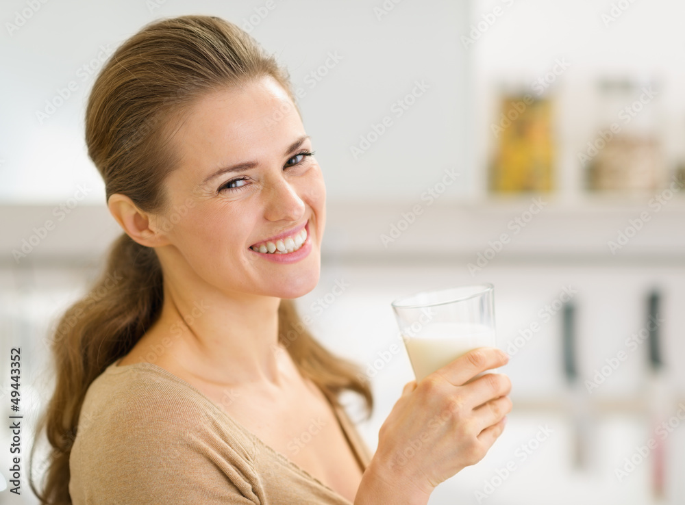 Portrait of smiling young woman with glass of milk in kitchen Portrait of smiling young woman with glass of milk in kitchen