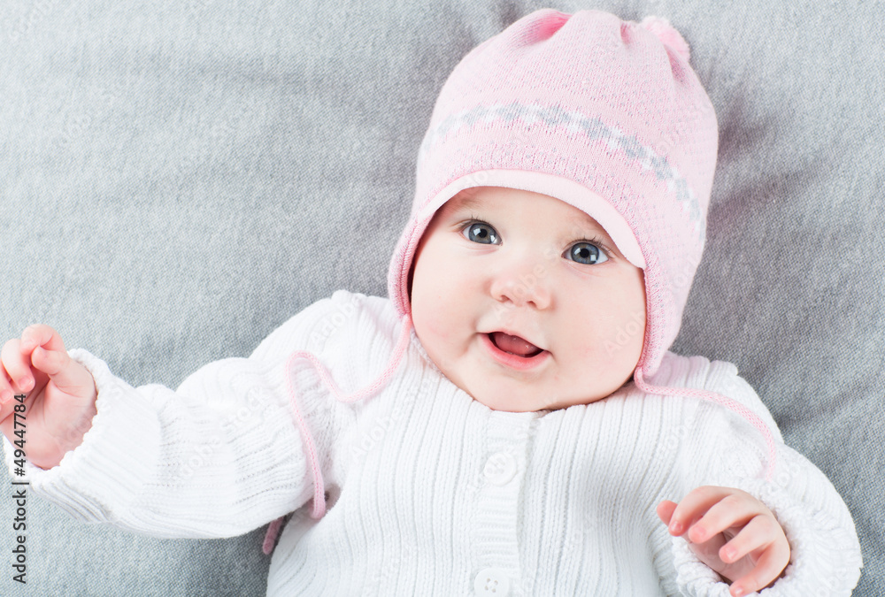 Sweet baby girl on a grey blanket wearing a pink hat Sweet baby girl on a grey blanket wearing a pink hat