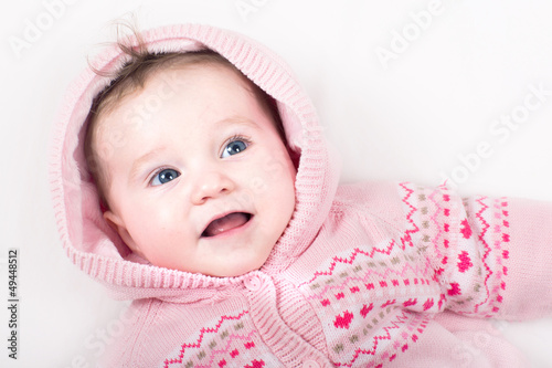 Funny little baby girl in a pink jacket with hearts pattern