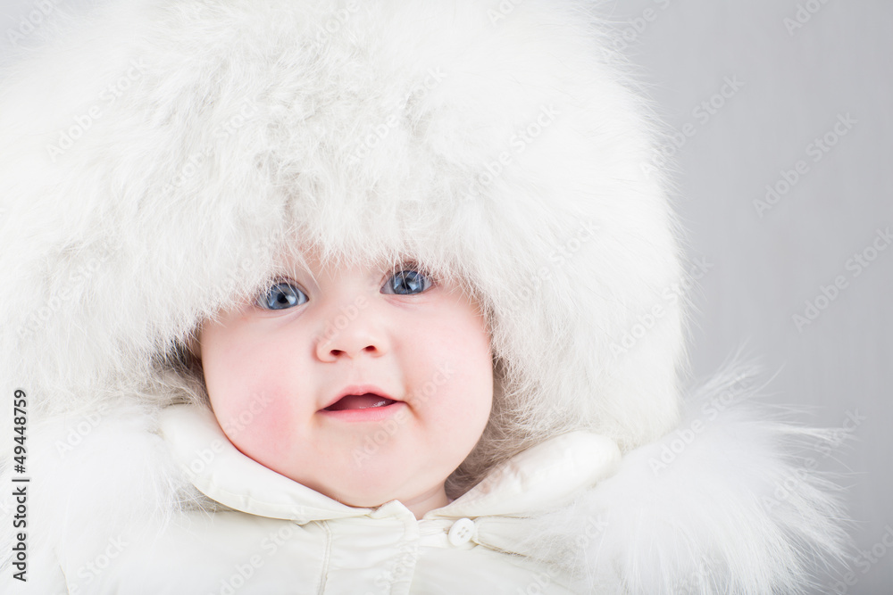 Close up portrait sweet baby in white fur hat and snow suit Close up portrait sweet baby in white fur hat and snow suit