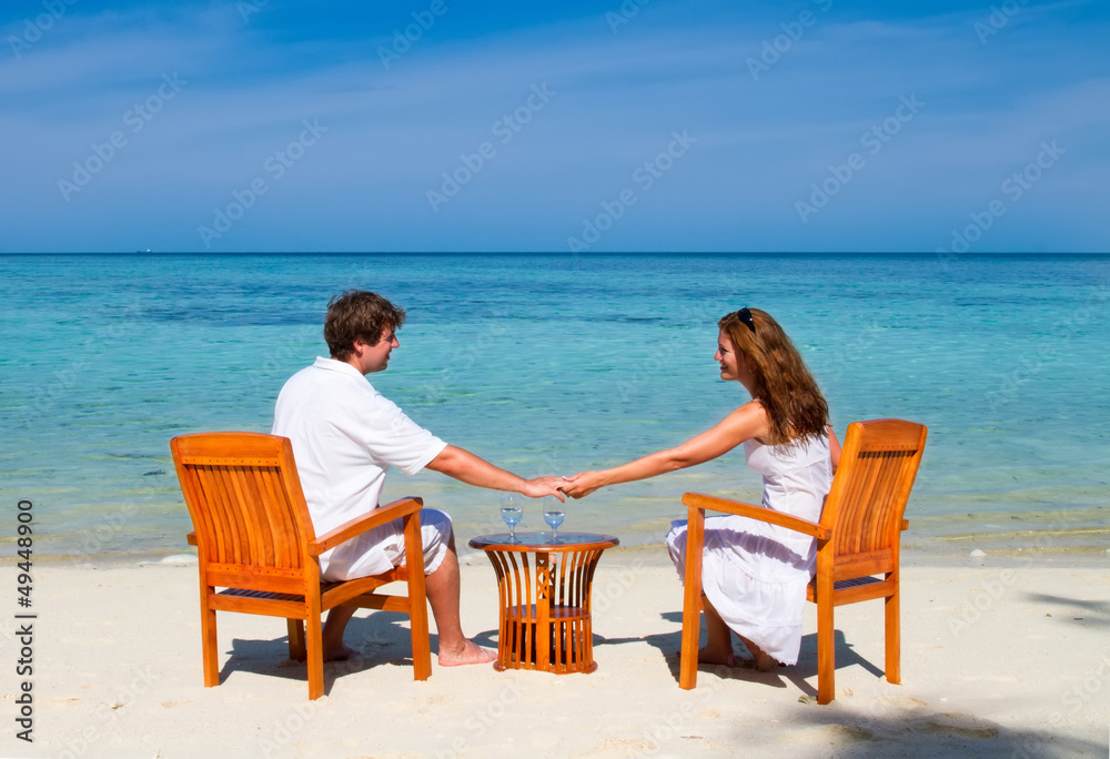Young beautiful couple enjoying cocktails on a tropical beach Young beautiful couple enjoying cocktails on a tropical beach