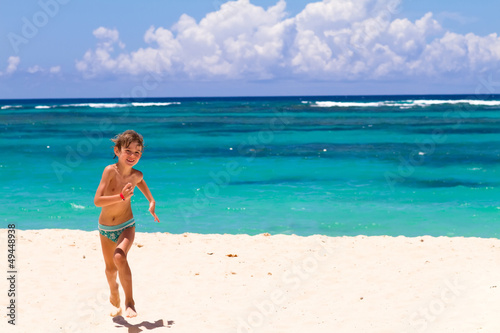 Boy running on a tropical beach with turquoise water