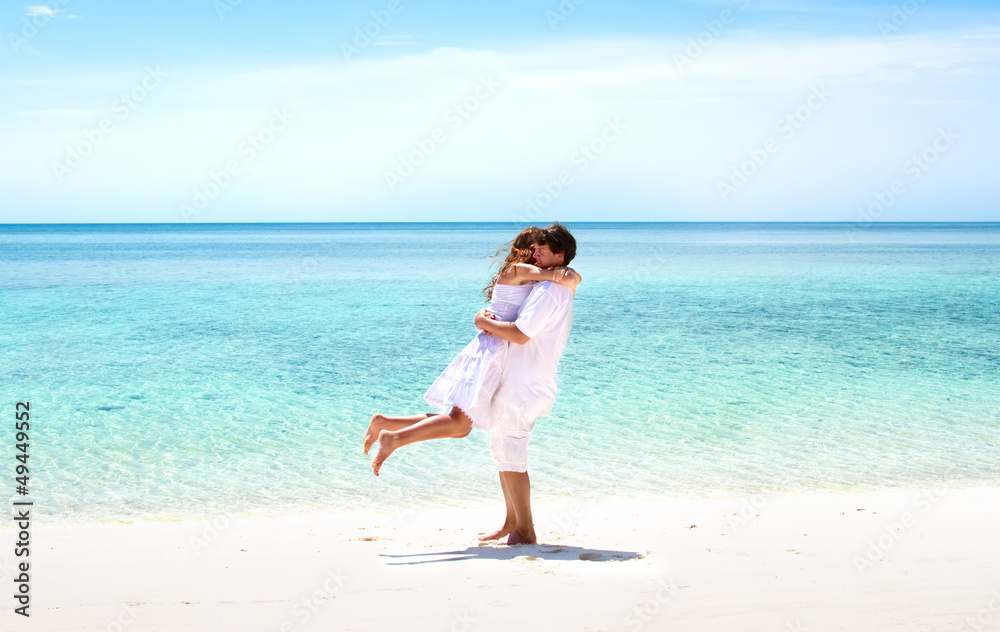 Beautiful young couple hugging on a stunning tropical beach Beautiful young couple hugging on a stunning tropical beach