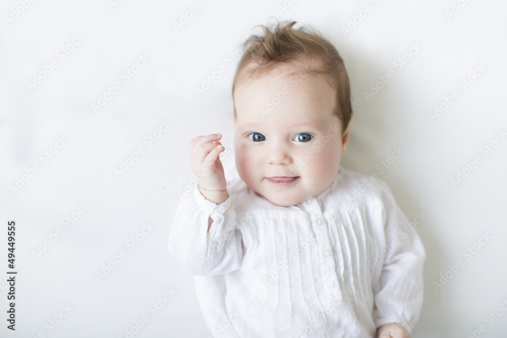 Beautiful baby blue eyes in white dress onwhite blanket