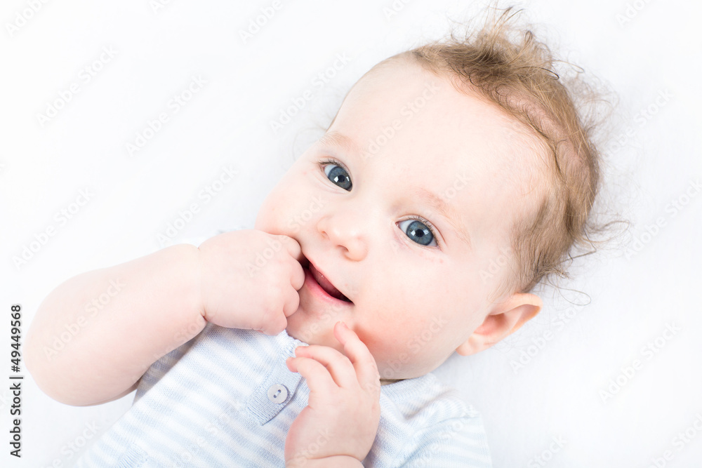 Sweet baby girl in blue knitted dress sucking on finger Sweet baby girl in blue knitted dress sucking on finger