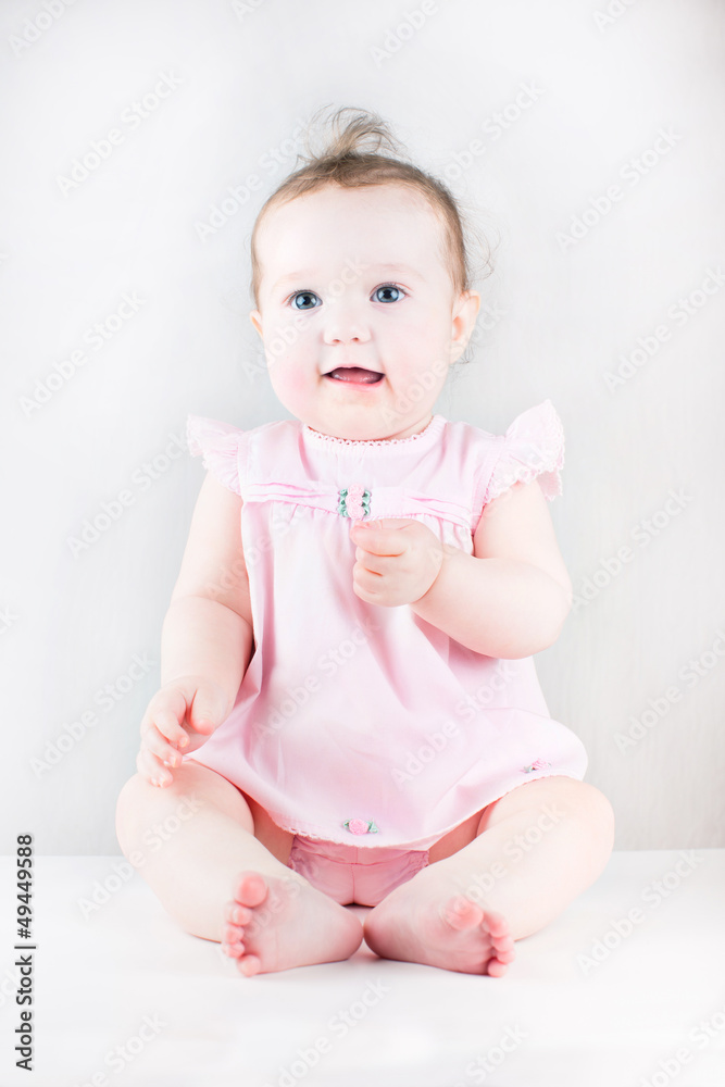 Cute baby girl sitting and wearing a pink dress Cute baby girl sitting and wearing a pink dress