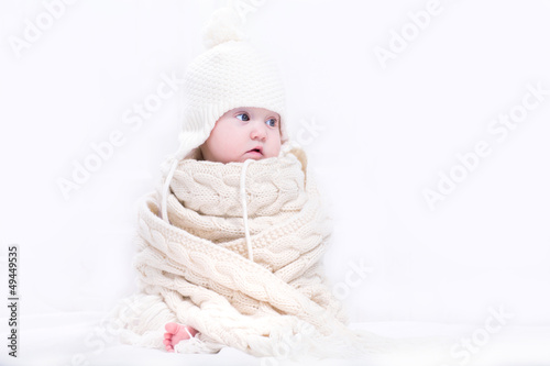 Cute baby in a big knitted scarf and hat