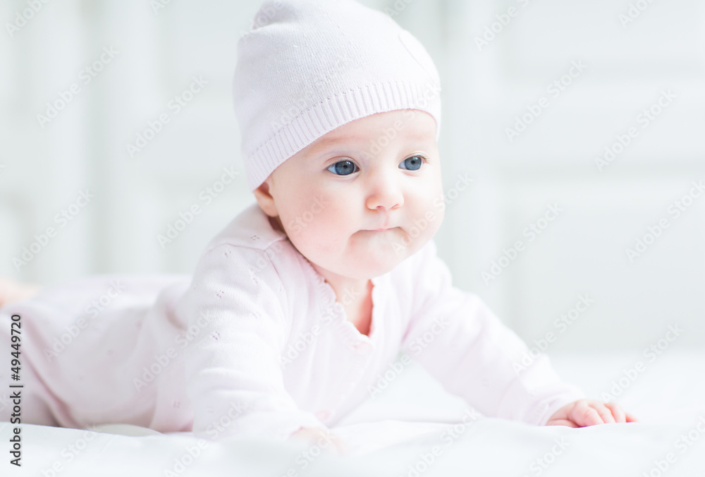 Sweet baby girl lying on tummy wearing pink cardigan