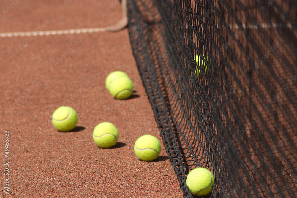 Ground court with yellow tennis balls before net closeup