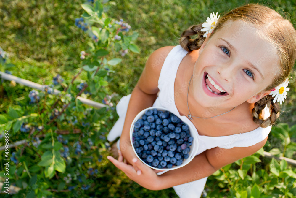 Blueberries - Girl with ripe blueberries in the garden