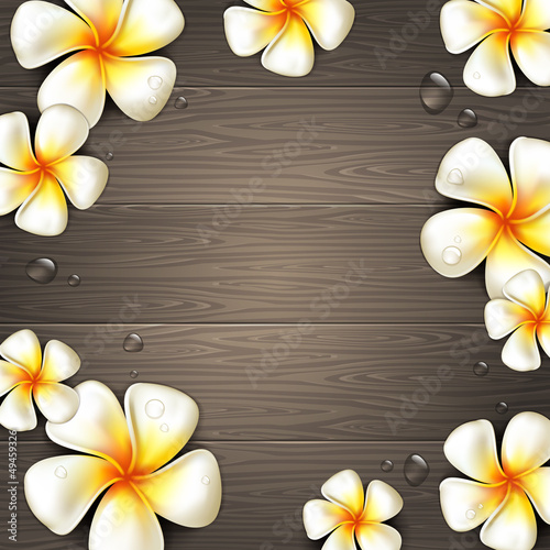 Tropical flowers and water drops on a wooden background