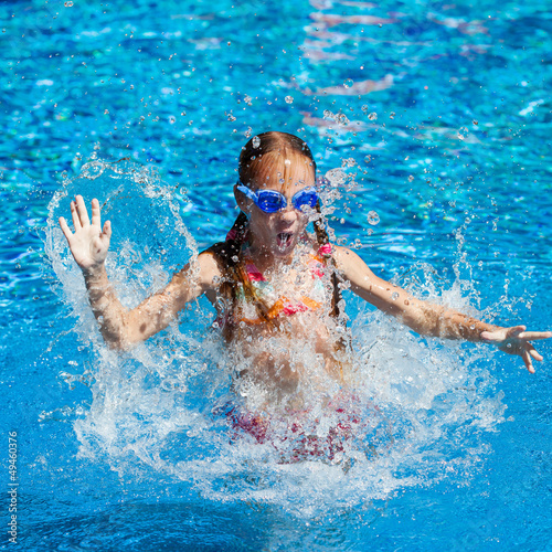 happy little girl splashing around in the pool