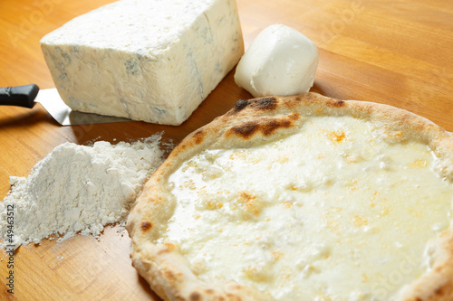 Typical Italian Pizza, ingredients in background on wood table
