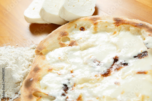 Italian Pizza, ingredients in the background on a wood table