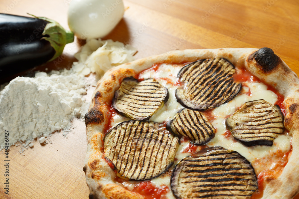 Italian Pizza, ingredients in the background on a wood table Italian Pizza, ingredients in the background on a wood table