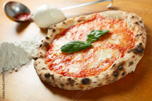 Italian Pizza, ingredients in the background on a wood table