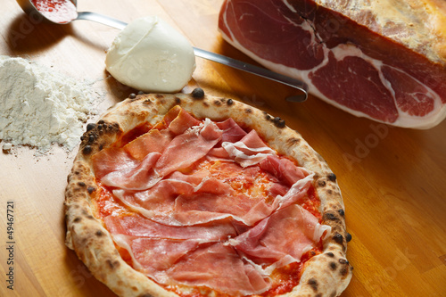 Italian Pizza, ingredients in the background on a wood table