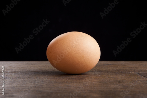 egg on a wooden table on black background