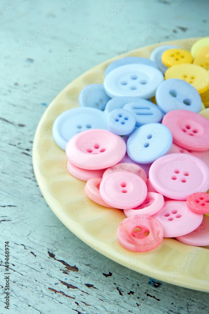Pink and blue buttons on a light yellow plate Pink and blue buttons on a light yellow plate