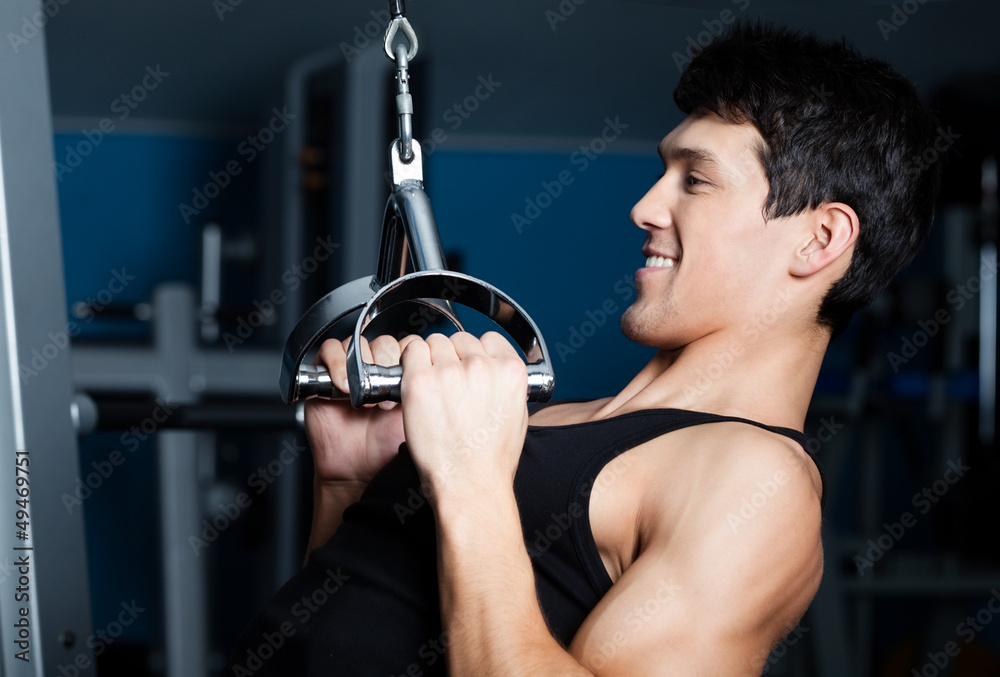 Athletic young man works out on simulator in gym Athletic young man works out on simulator in gym