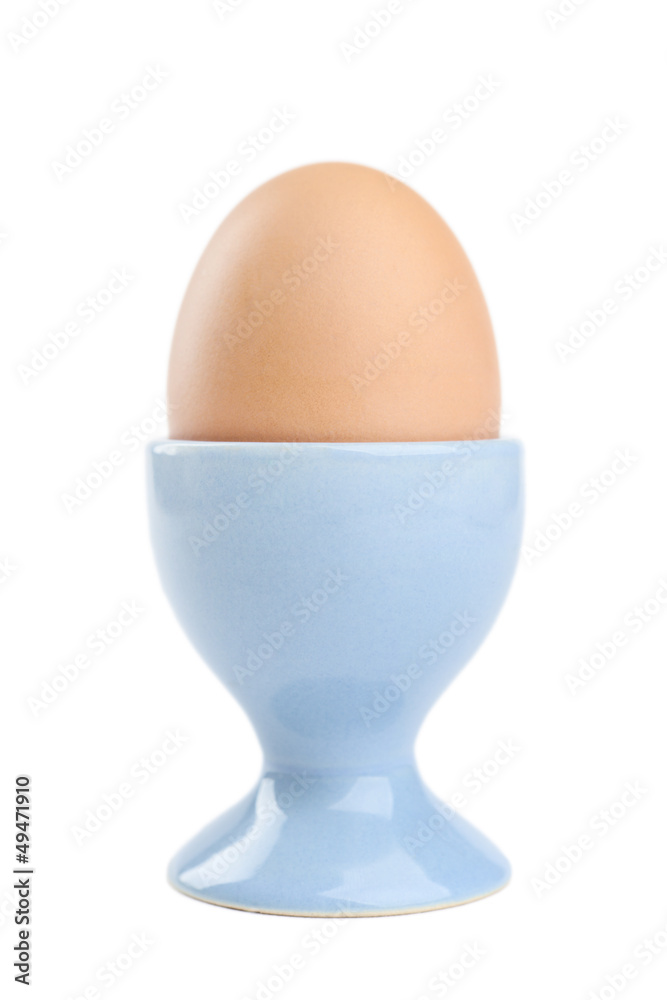 Colored easter egg in blue egg cup, isolated on white Colored easter egg in blue egg cup, isolated on white
