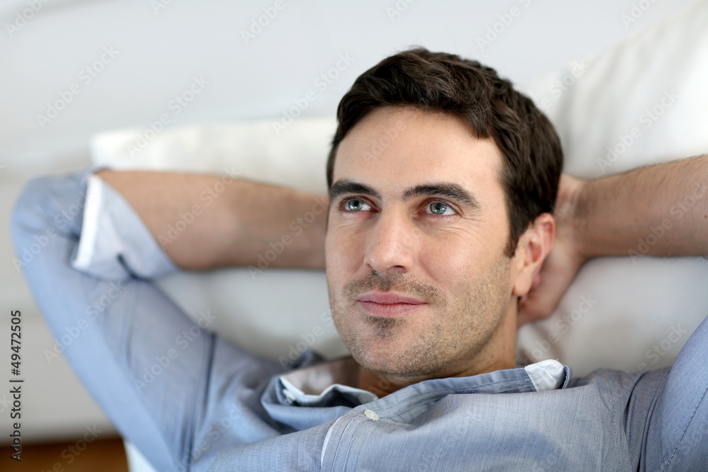 Fototapeta premium Man relaxing in sofa with arms behind head