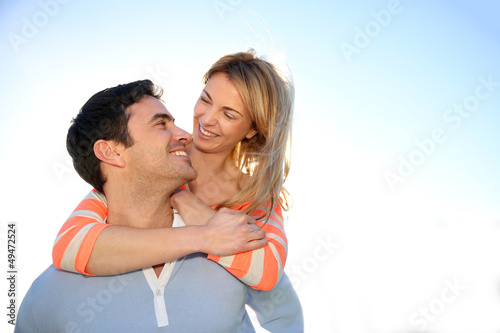 Man giving piggyback ride to girlfriend by the sea