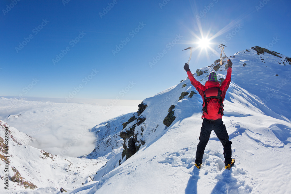 Mountaineer reaches the top of a snowy mountain