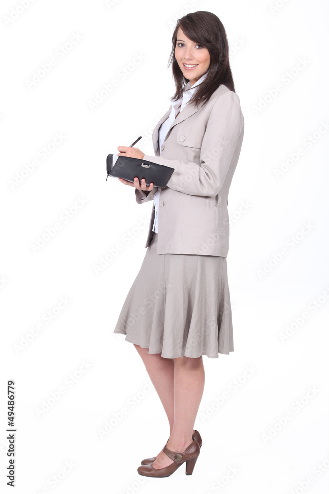 Woman in a skirt suit writing in a personal organizer