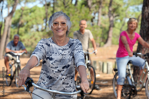 old woman and three other people doing bike in the forest © auremar