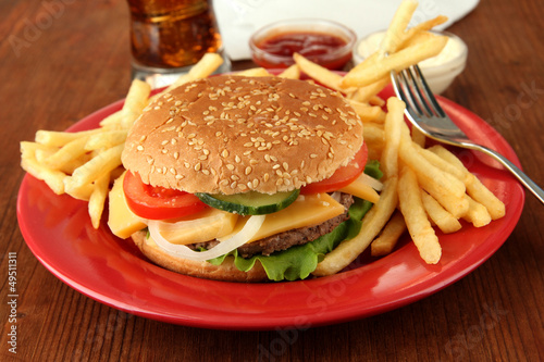 Tasty cheeseburger with fried potatoes and cold drink,