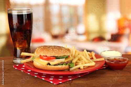 Tasty cheeseburger with fried potatoes and cold drink,