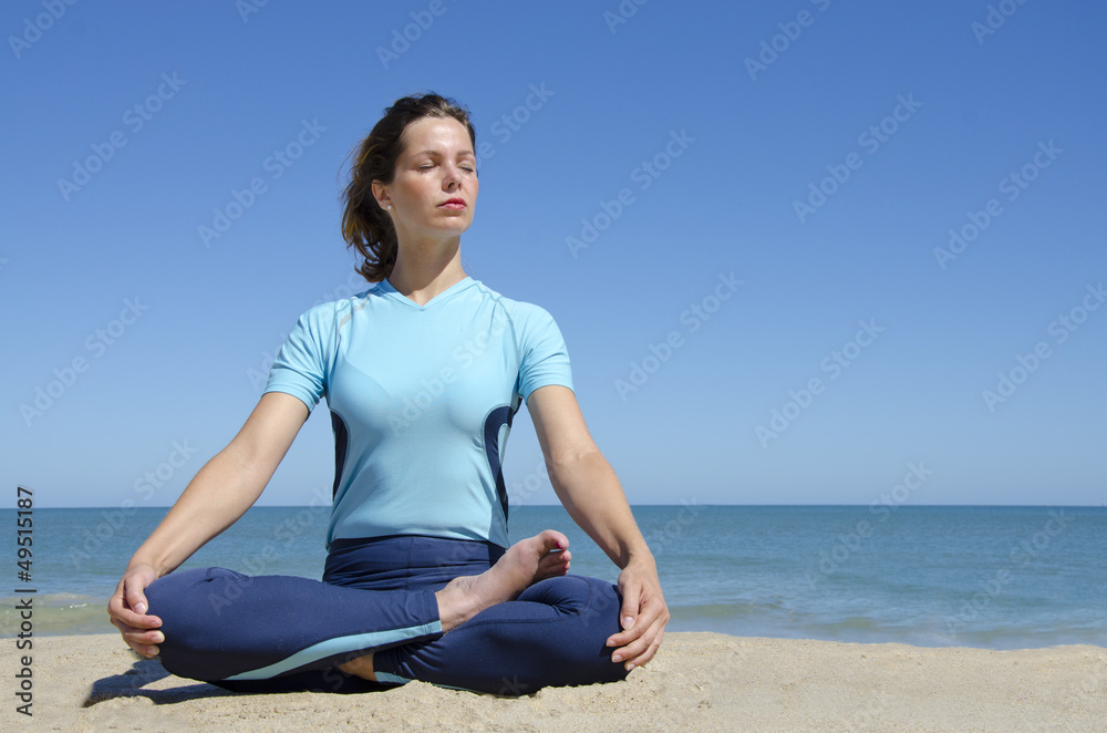 Yoga girl in cross-legged lotus pose at beach