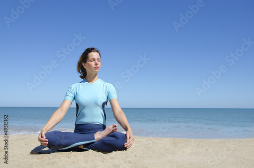 Sexy girl in cross-legged yoga lotus pose at beach
