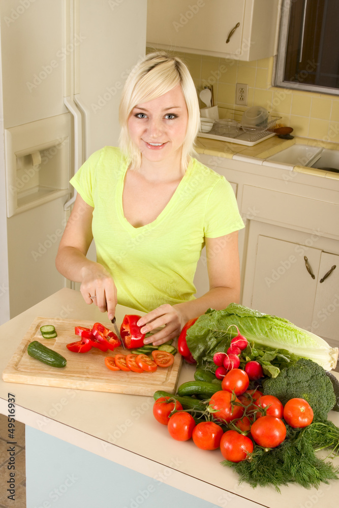 Young blond woman slicing vegetables on kitchen Young blond woman slicing vegetables on kitchen