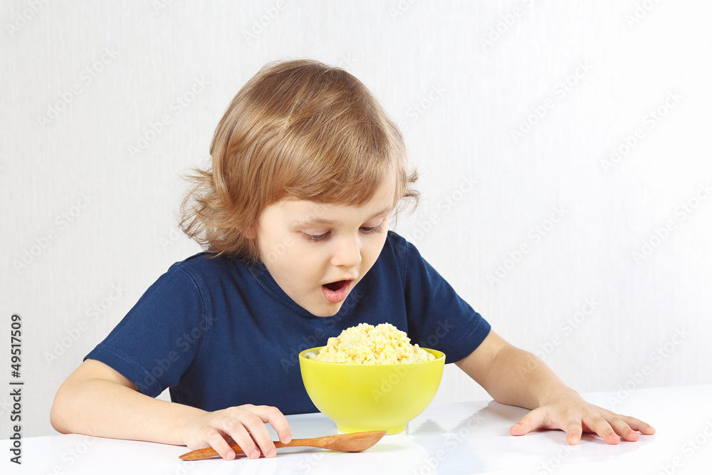 Little blonde child is going to breakfast a millet porridge Little blonde child is going to breakfast a millet porridge